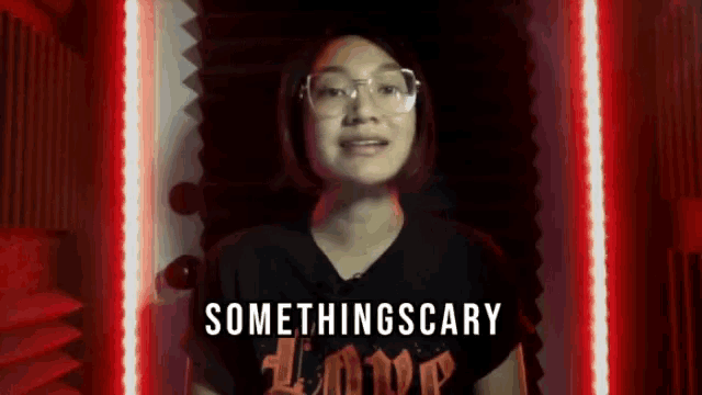 a woman wearing glasses and a black shirt that says something scary on it