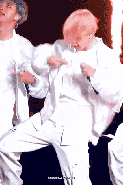 a man with pink hair is holding a microphone while dancing on stage .