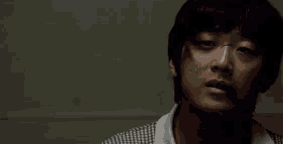 a close up of a man 's face in a dark room with a blurred background .