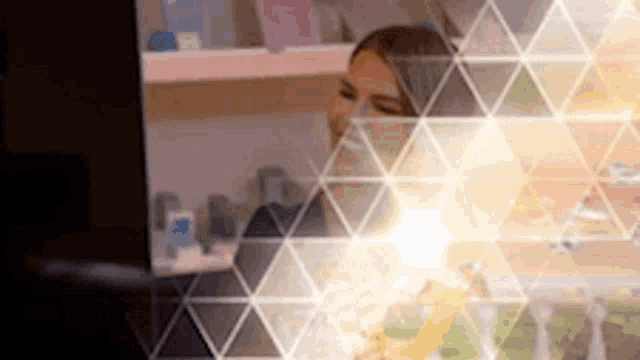 a woman is standing in front of a computer screen with a triangle pattern on it .