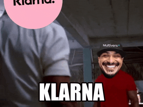 a man wearing a hat that says multivers on it smiles in front of a pink circle that says klarna