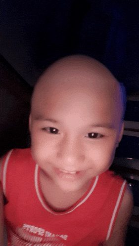 a young boy with a shaved head wearing a red shirt that says ' hope ' on the front
