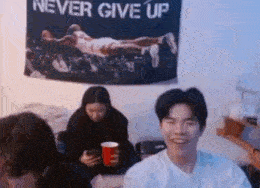 a group of people are sitting in a room with a banner that says `` never give up '' .