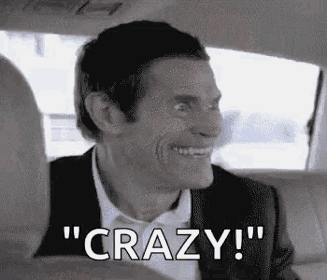 a man is sitting in the back seat of a car and smiling .