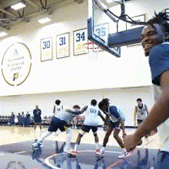 a group of basketball players are playing on a court with numbers 30 31 34 and 35 on the wall behind them