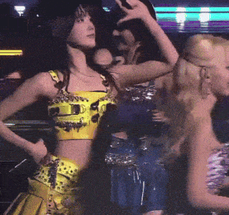 a woman in a yellow crop top is dancing in a dark room