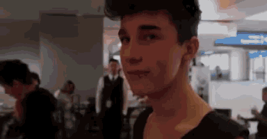 a young man in a black shirt is looking at the camera while standing in an airport