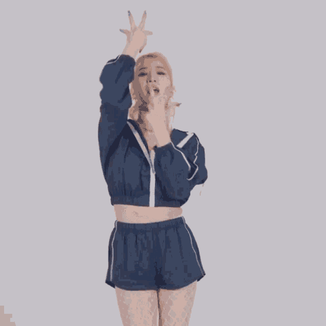 a woman wearing a blue jacket and shorts is making a peace sign