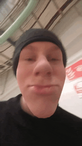 a man wearing a black beanie is making a face