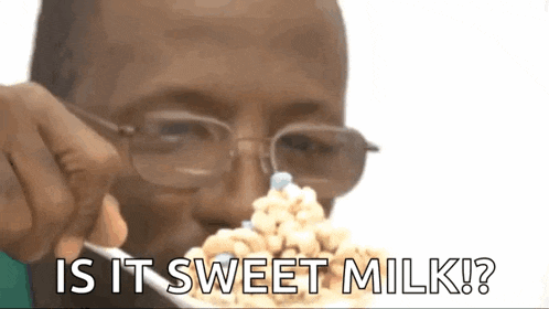 a man with glasses is eating cereal with a fork and the words `` is it sweet milk ? ''