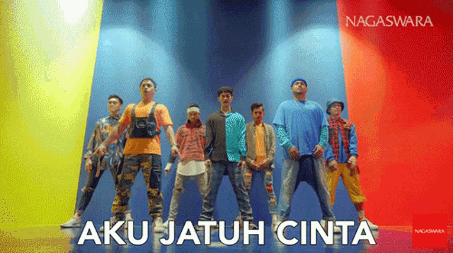 a group of men are standing in front of a colorful wall with aku jatuh cinta written on the bottom right