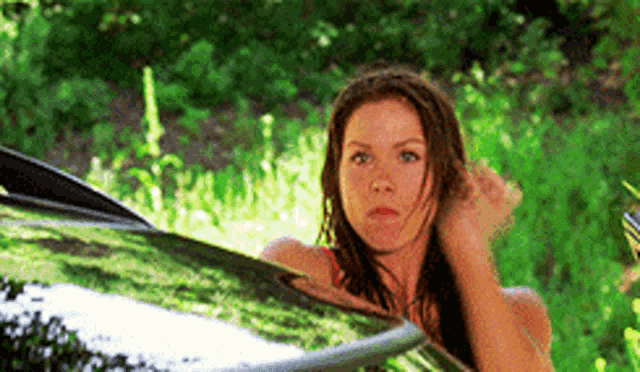 a woman is standing next to a car in the grass .