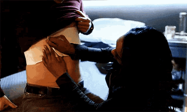 a woman is touching a man 's stomach with a bandage .