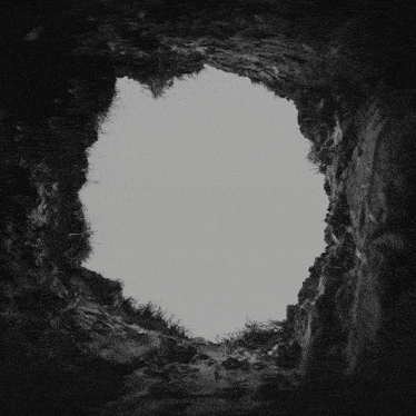 a black and white photo of a hole in the ground looking up to the sky