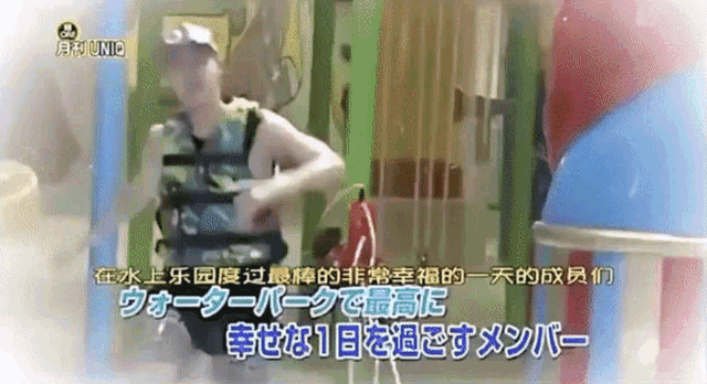a man in a camouflage vest is standing in a room with chinese writing on it