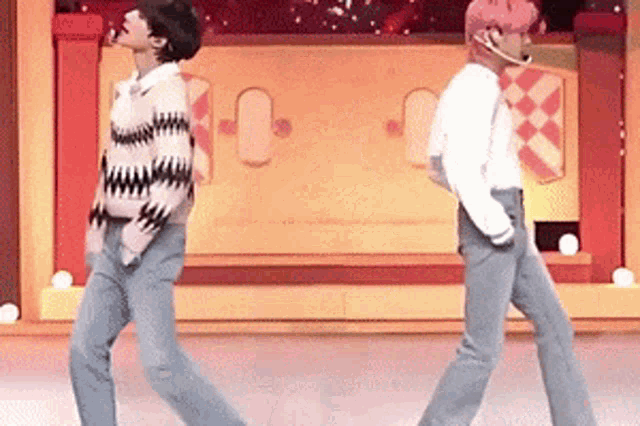 two men are dancing together on a stage in front of a yellow wall .