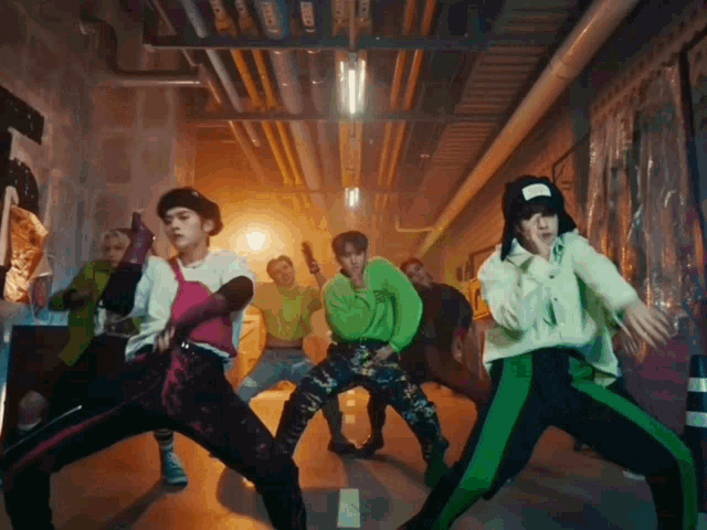 a group of people are dancing in a hallway and one of them is wearing a white hat with the letter t on it
