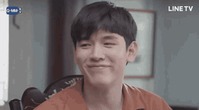 a young man is smiling while sitting in a chair with a line tv logo in the background .