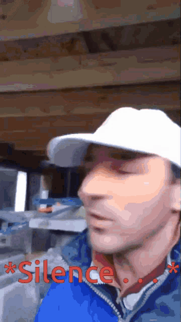 a man wearing a white hat and a blue jacket with the word silence in red