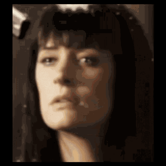 a close up of a woman 's face with a serious look on her face in a blurry photo .