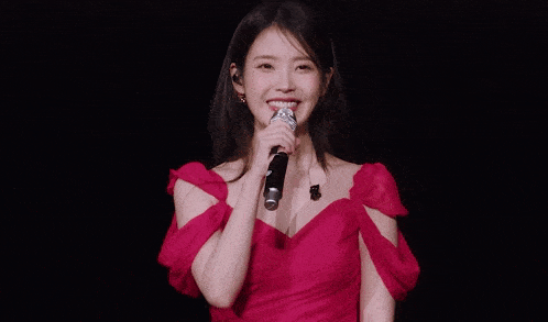 a woman in a red dress is holding a microphone and smiling .