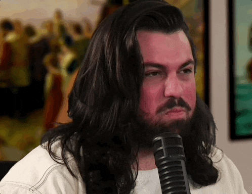 a man with long hair and a beard is singing into a microphone .