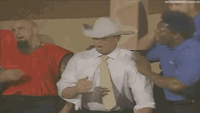 a man wearing a cowboy hat and white gloves is being held by a group of people