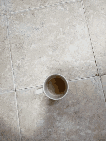 a cup of coffee is sitting on a tile floor