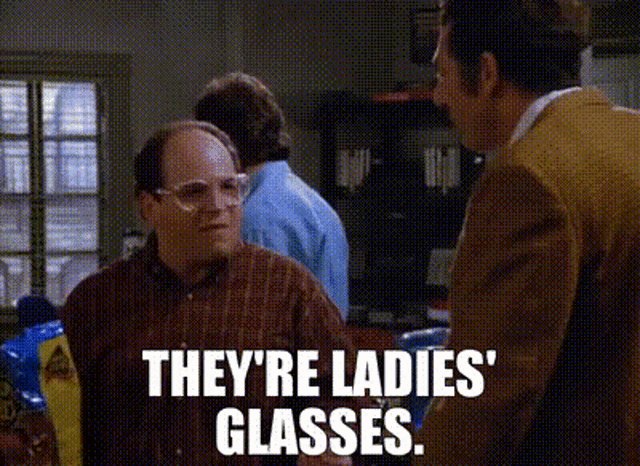 a man wearing glasses is talking to another man in a kitchen .
