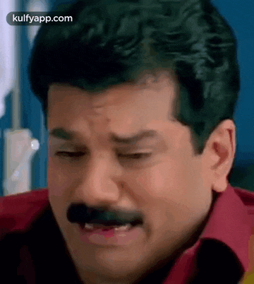 a man with a mustache and a red shirt is making a funny face .