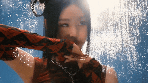 a woman is standing in front of a window with water drops coming out of it
