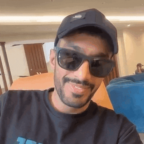 a man with a beard wearing sunglasses and a hat is smiling