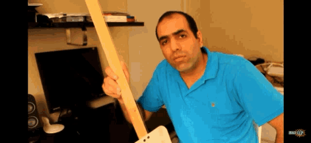 a man in a blue shirt is holding a wooden stick