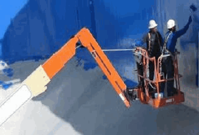 two men are painting a blue wall with a crane .
