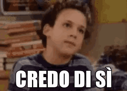a young boy is making a funny face with the words credo di si written on his face .