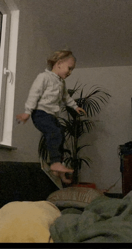a little girl is jumping in the air in front of a palm tree