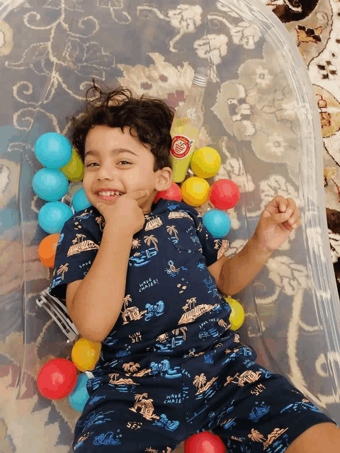 a young boy in a shirt that says have a nice day is playing with balls