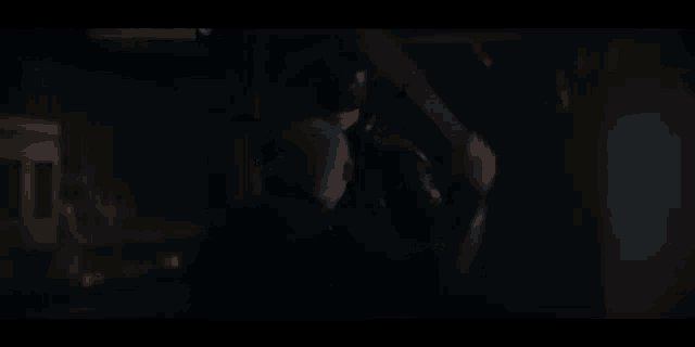 a man is holding a megaphone in a dark room while another man looks on .