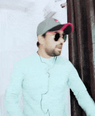 a man wearing a hat and sunglasses is standing in a room