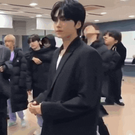a man in a black suit is standing in front of a group of people .