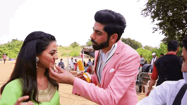 a man in a pink suit is touching the face of a woman