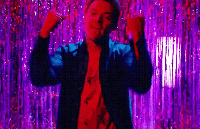 a man is dancing in front of a purple curtain in a club .