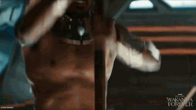 a man without a shirt is hanging upside down with the words wakanda forever on the bottom right