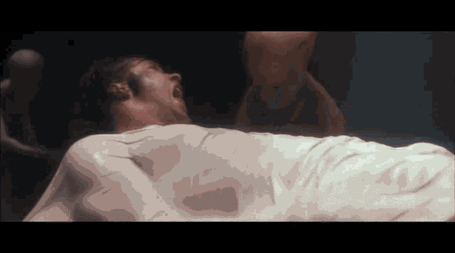 a man in a white cloth is laying on the floor with his mouth open