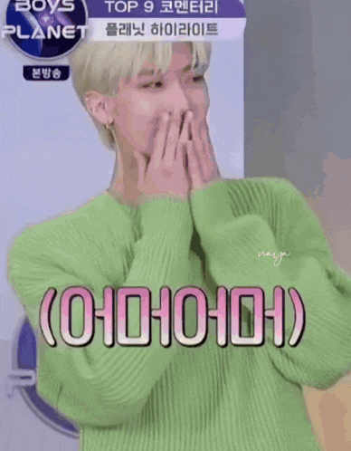 a man in a green sweater is holding a pink heart in front of his face ..