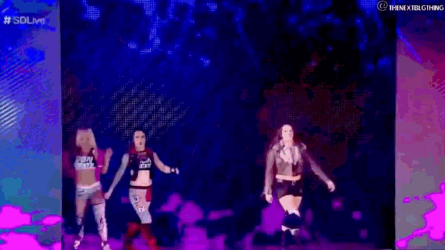 a group of women are dancing on a stage in a dark room .
