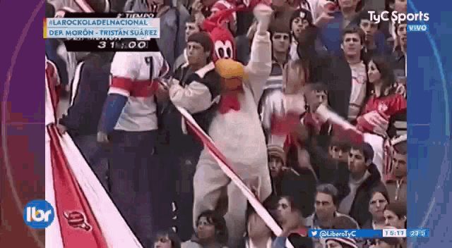 a man in a chicken costume holds a flag in front of a crowd of people .
