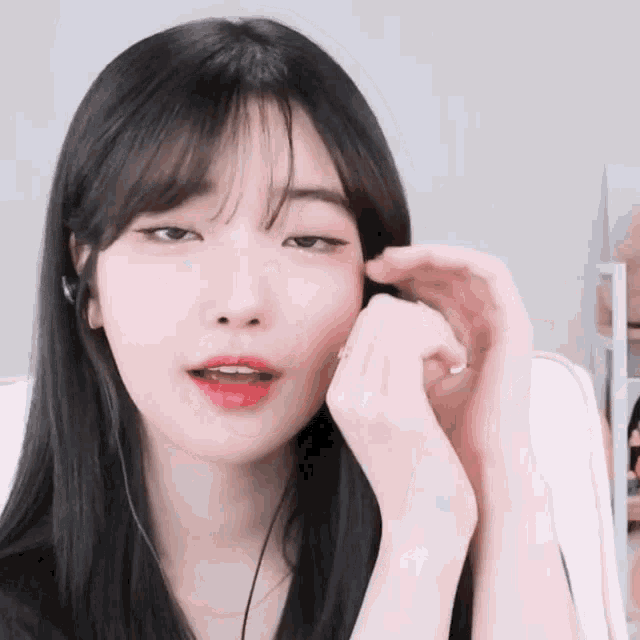 a girl with long black hair and bangs is wearing headphones and a ring on her finger