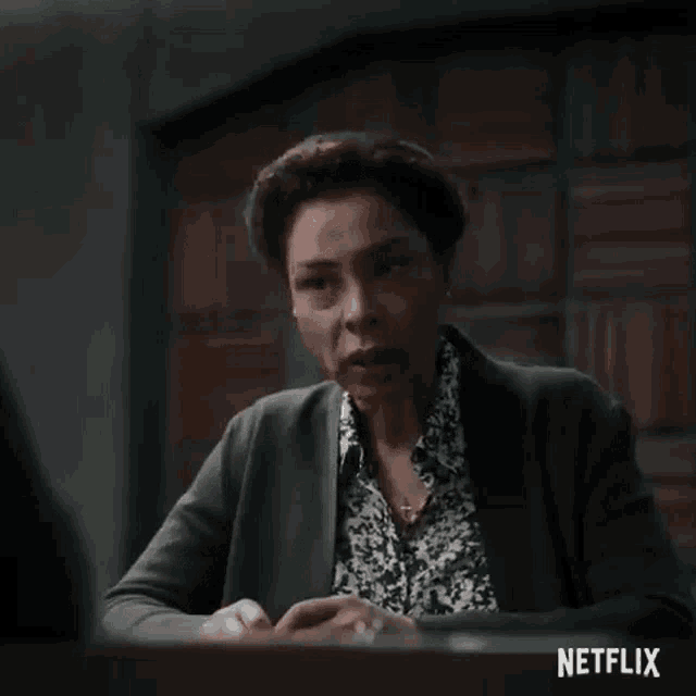 a woman in a green sweater is sitting at a table talking to another woman .