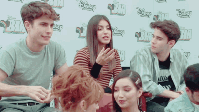 a group of people are sitting in front of a wall that says disney on it